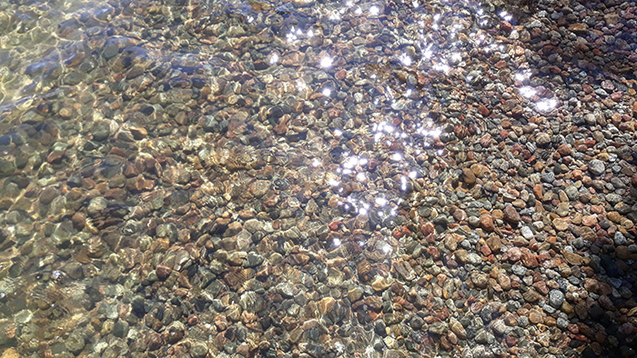 Kristallinkirkasta vettä kivikkorannalla aurinkoisessa säässä