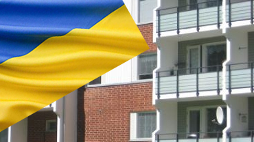 Ukrainan lippu vasemmalla sivuttain, kerrostalo taustalla
