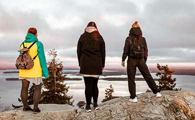 Kuvassa kolme nuorta opiskelijaa ihastelee maisemia Keski-Karjalassa. Kuva otettu Nurmeksen läheltä.
